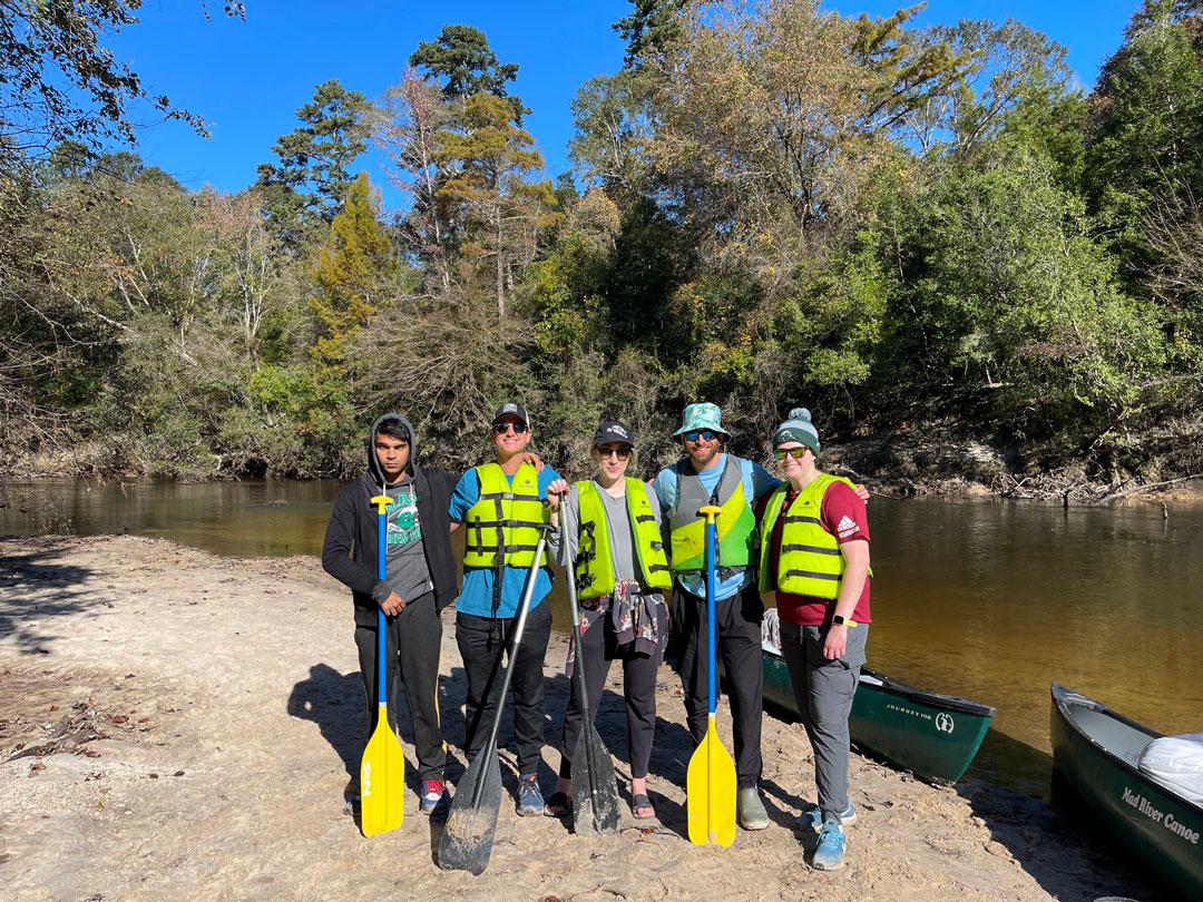 Group photo of TRC members posing with canoe paddles on Blackwater Creek