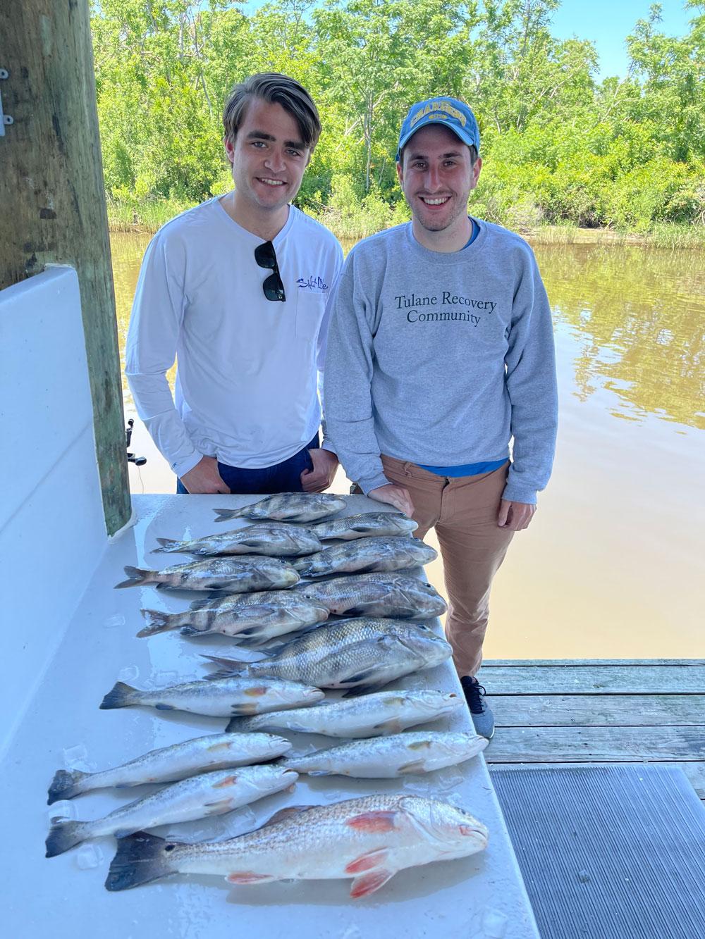 Two students smiling next to caught fish