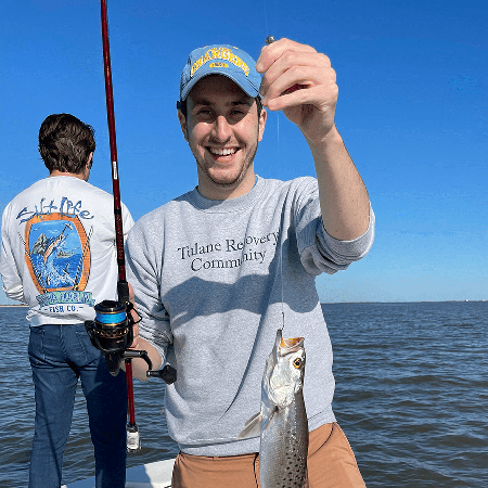 A Tulane Recovery Community participant holding up a fish he caught