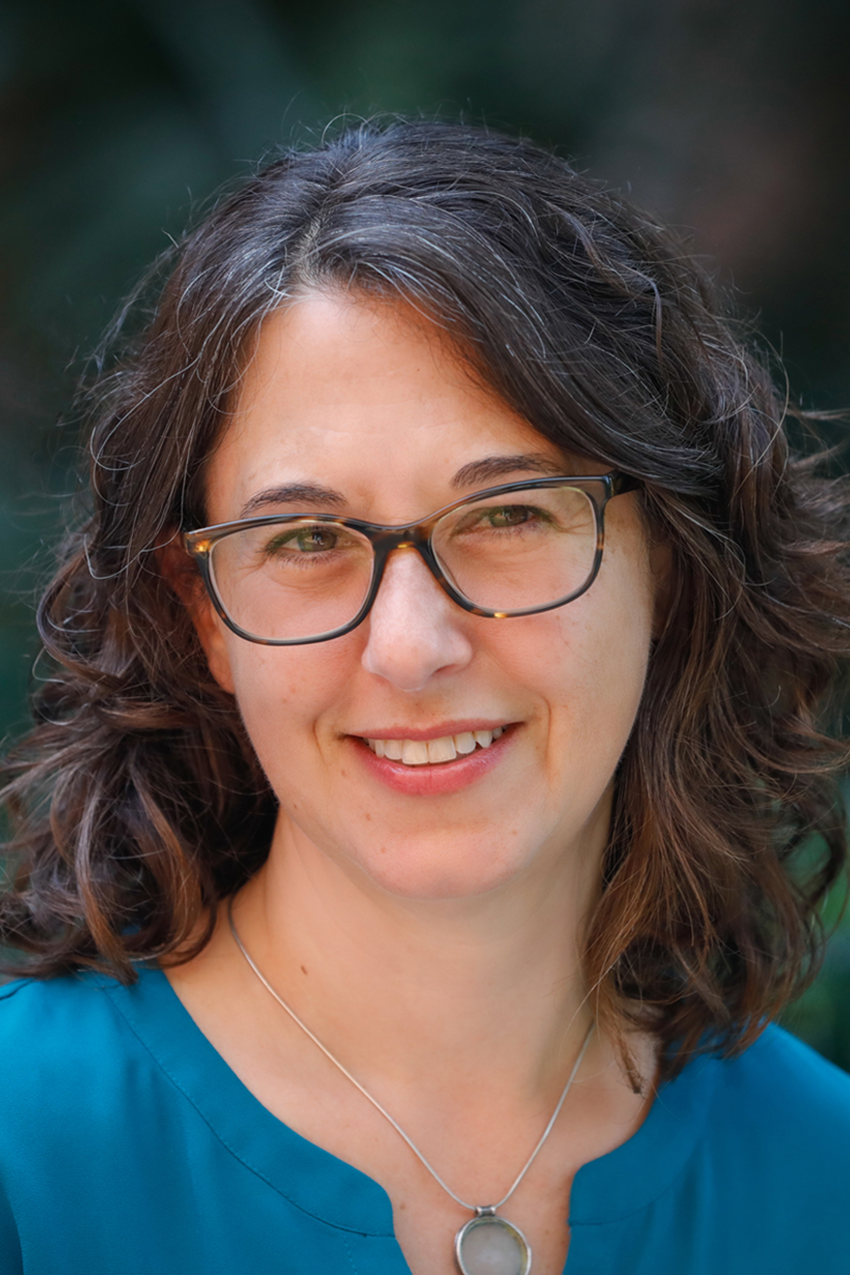 Portrait of Tamar Starck wearing a blue blouse and gently smiling