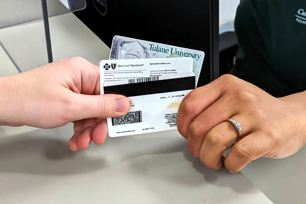 Student handing staff their Tulane splash card, insurance card, and state ID