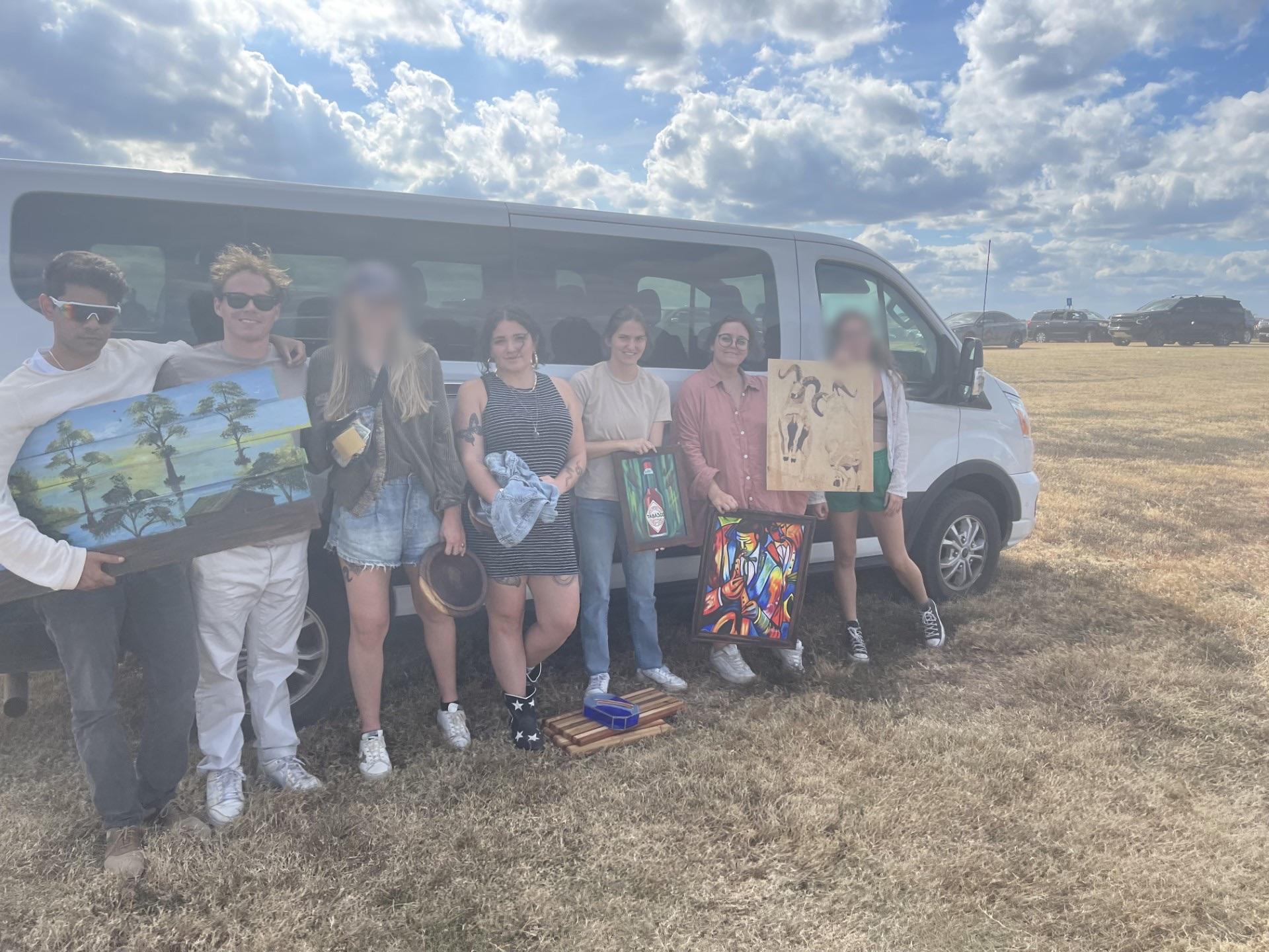 Group photo of TRC members holding artwork in front of van at the 2022 Angola Rodeo Show
